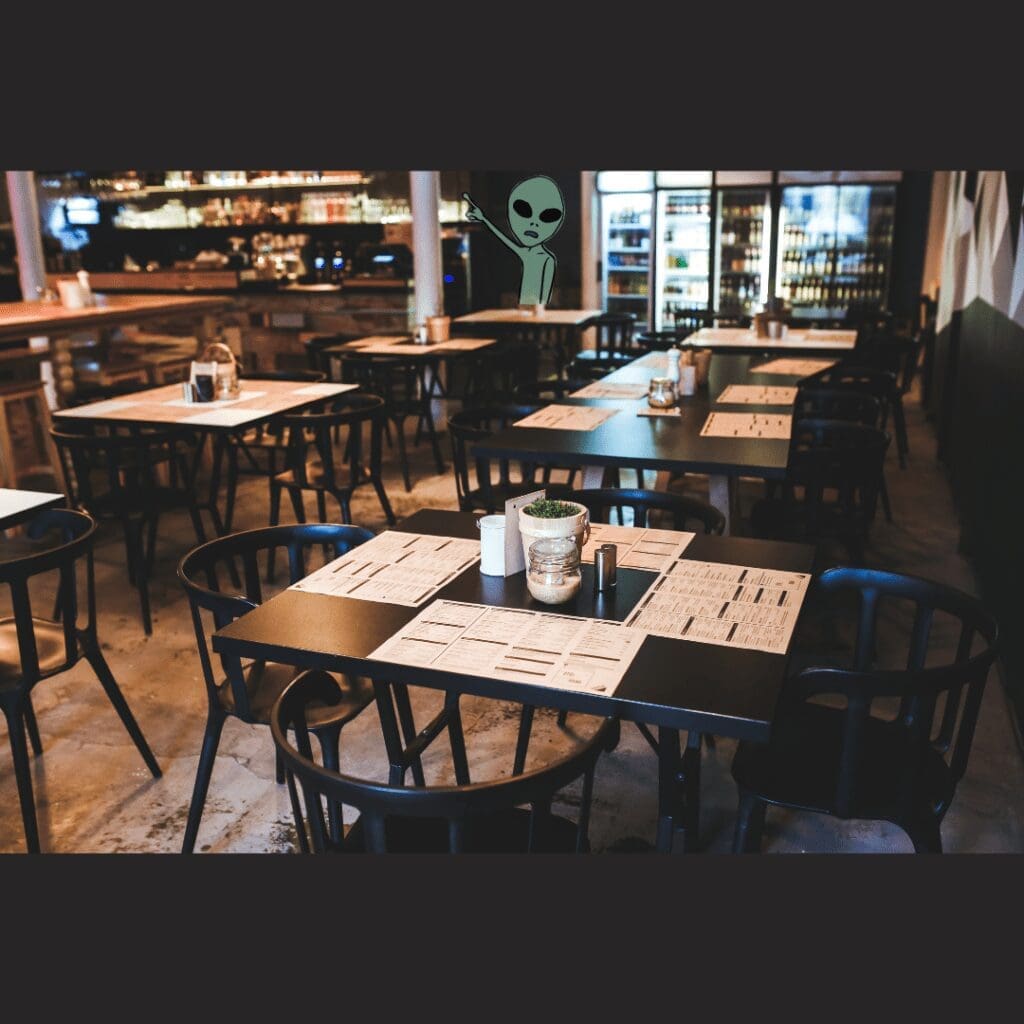 A Taste of Online Triumph: Strategies for Roswell Restaurant Excellence 2 A Roswell Restaurant, vacant with black chairs and tables, menus at every place setting, an alien painted on the far wall